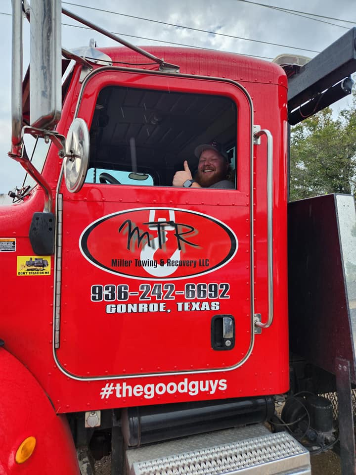 Smiling towing operator sitting inside a professional tow truck